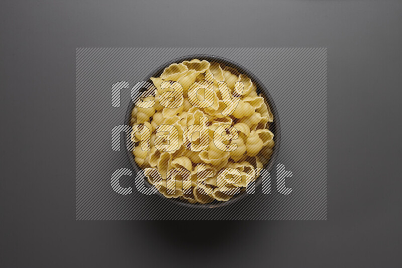 Snails pasta in a pottery bowl on grey background