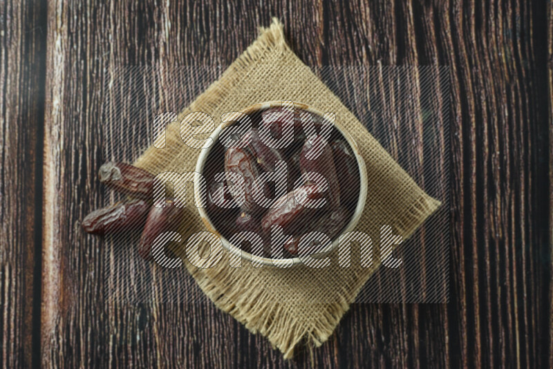 Dates in different bowls (wooden, pottery and glass) on wooden background