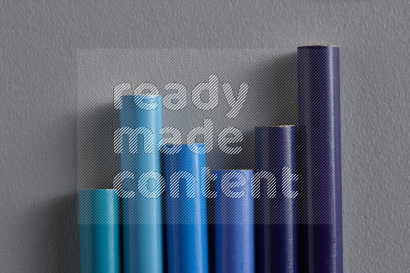 A collection of colored pencils arranged showcasing a gradient of blue hues on grey background