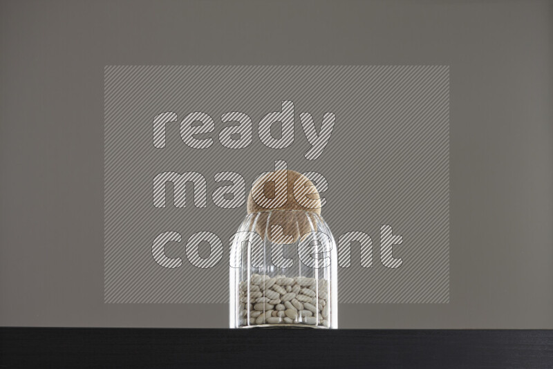 White beans in a glass jar on black background