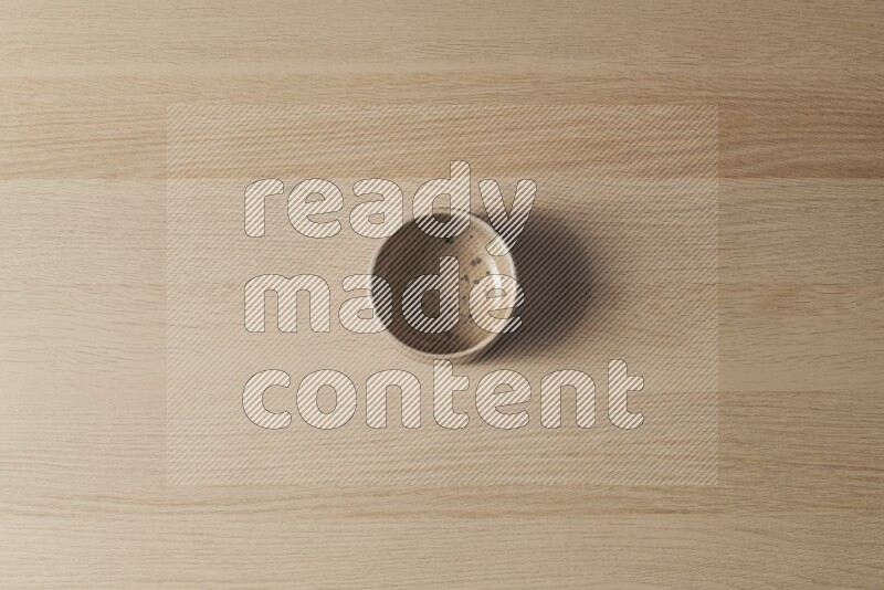 A multicolored pottery bowl on light wooden background