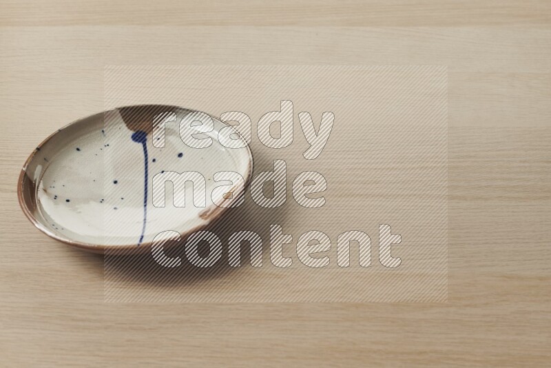 A multicolored pottery plate on light wooden background