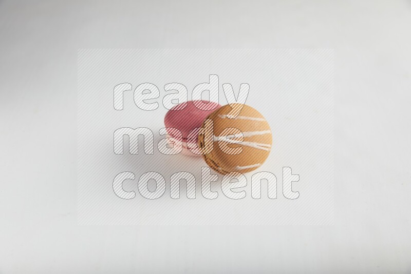 45º Shot of of two assorted Brown Irish Cream, and Pink Litchi Raspberry macarons on white background