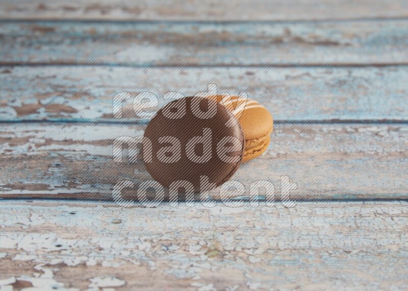 45º Shot of of two assorted Brown Irish Cream, and Brown Dark Chocolate macarons on light blue background