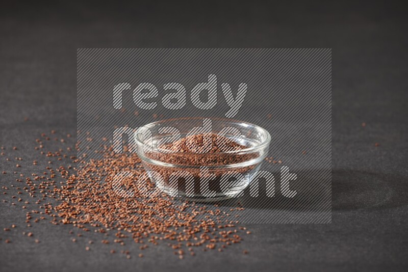 وعاء زجاجي ممتلئ ببذور حب الرشاد محاط بالبذور على أرضية سوداء