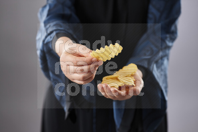 Woman in abaya holding different kinds of snacks in different positions