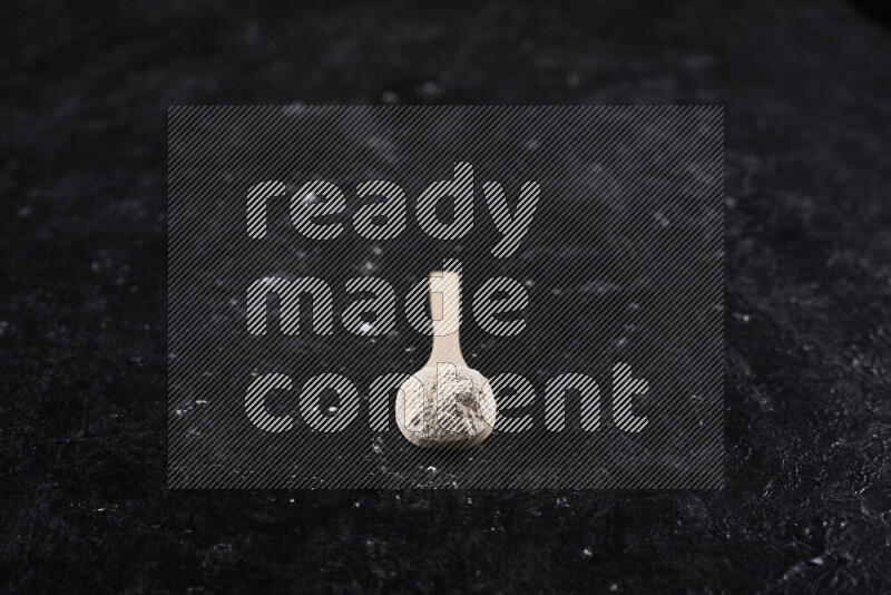 A wooden spoon full of onion powder on black background