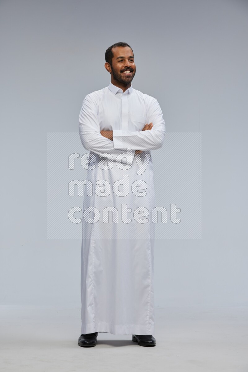 Saudi man wearing Thob standing with crossed arms on Gray background