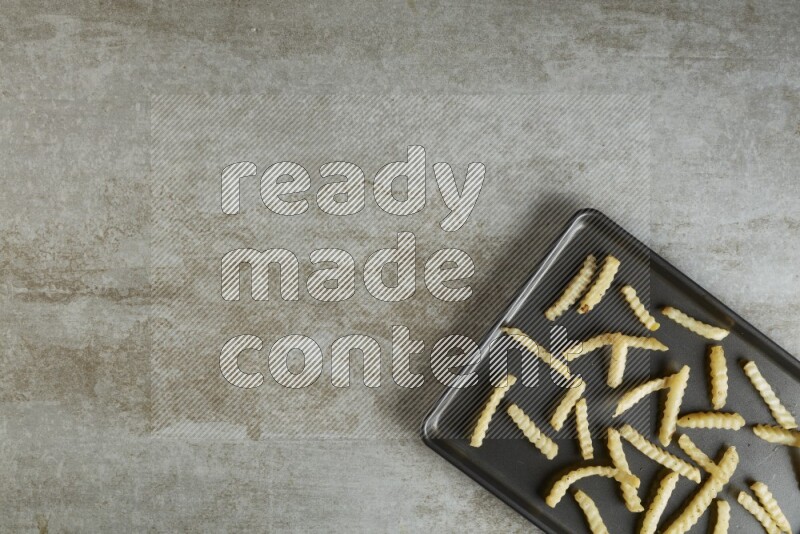 crinkle fries in a black stainless steel rectangle tray on grey textured counter top