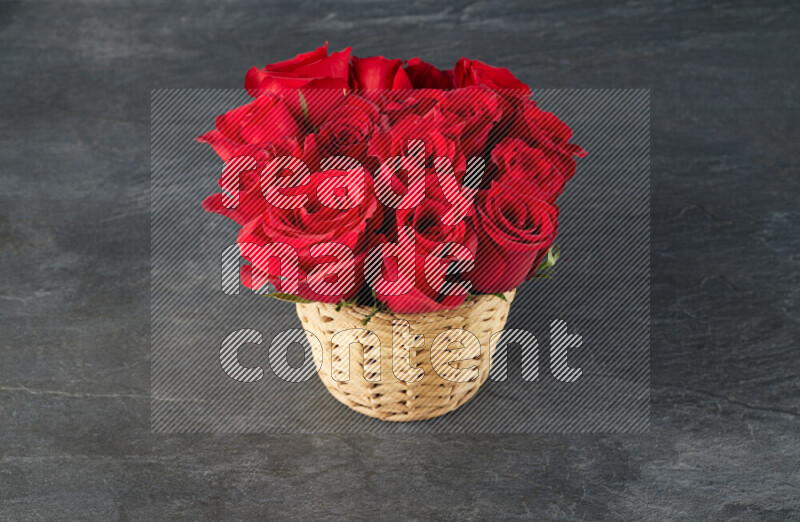 Vibrant red roses in a wicker basket on black marble background