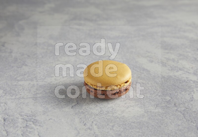 45º Shot of Yellow and Brown Chai Latte macaron on white  marble background