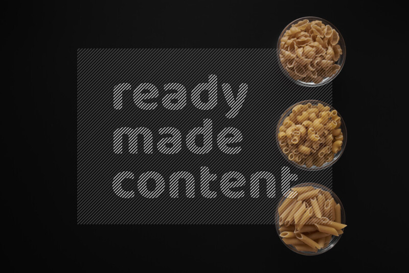 Different pasta types in 3 glass bowls on black background