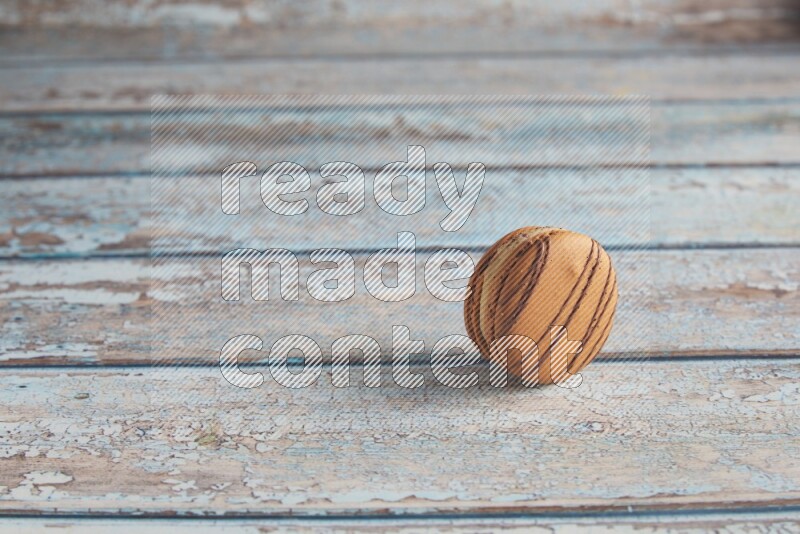 45º Shot of light brown Almond Cream macaron on light blue wooden background