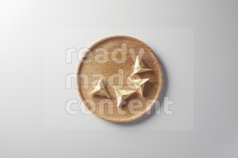 Four Sambosas on a wooden round plate on a white background