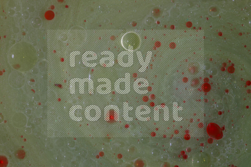 The image captures a dramatic splatter of red paint over a green backdrop