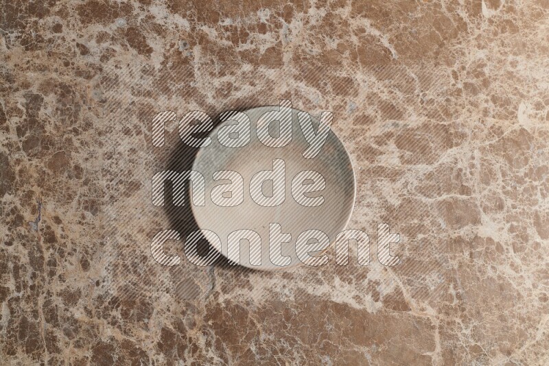 A multicolored pottery plate on beige marble background