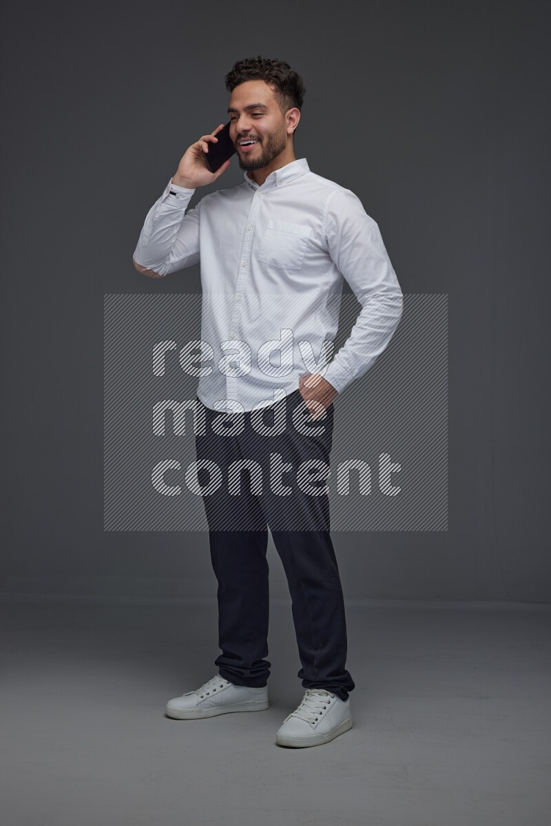 A man wearing smart casual talking in the phone eye level on a gray background