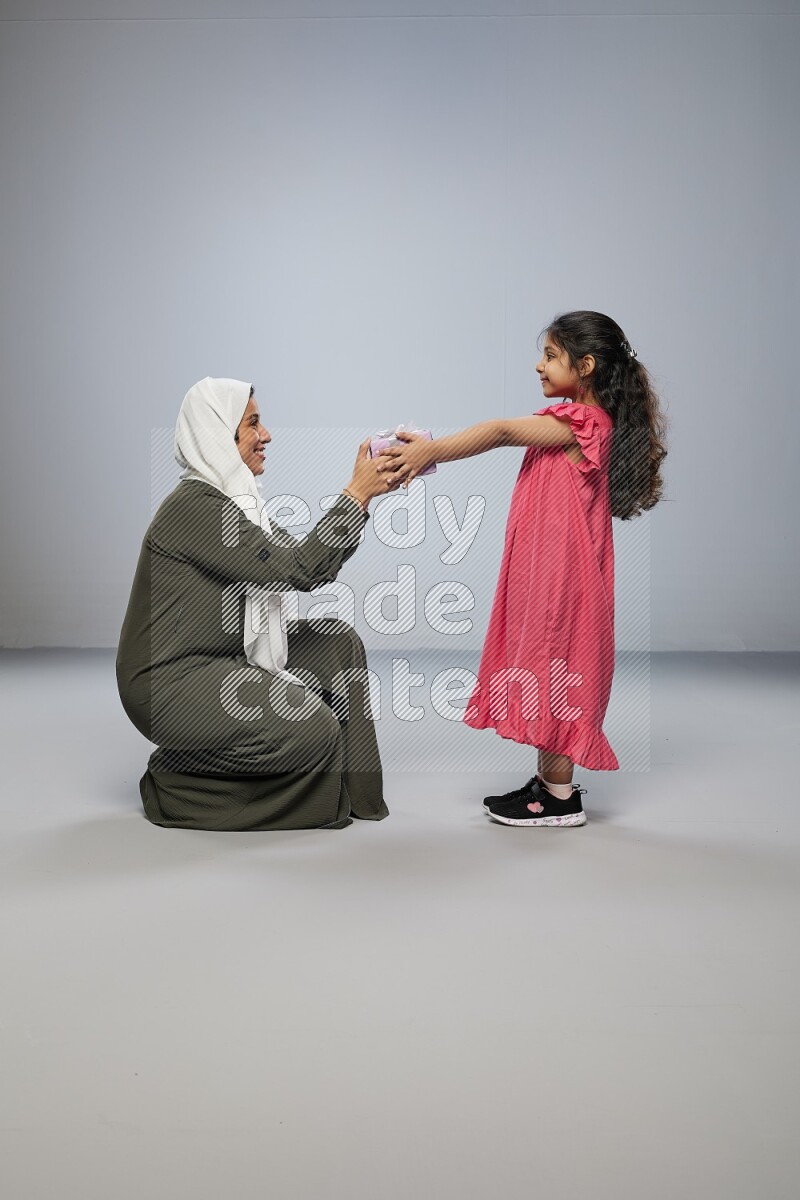 A girl giving a gift to her mother on gray background