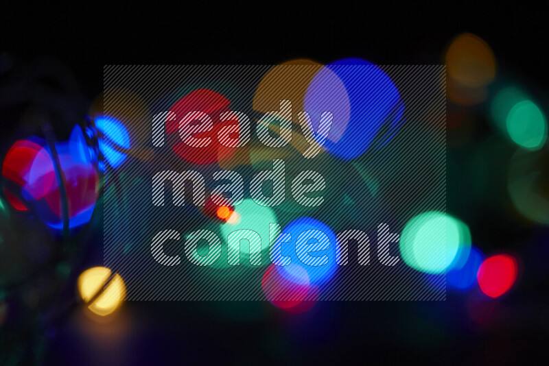 Light bulbs glowing against backdrop of multicolord bokeh