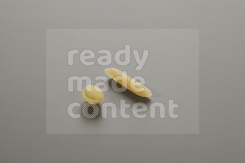 Shells pasta with other types of pasta on grey background