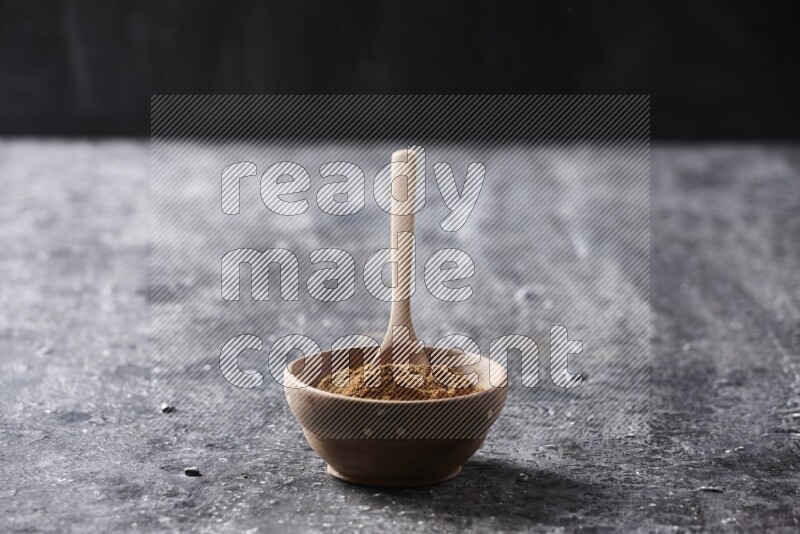 Wooden bowl full of cinnamon powder with a wooden spoon on a textured black background in different angles