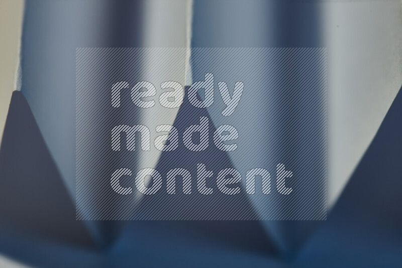 A close-up abstract image showing sharp geometric paper folds in blue gradients