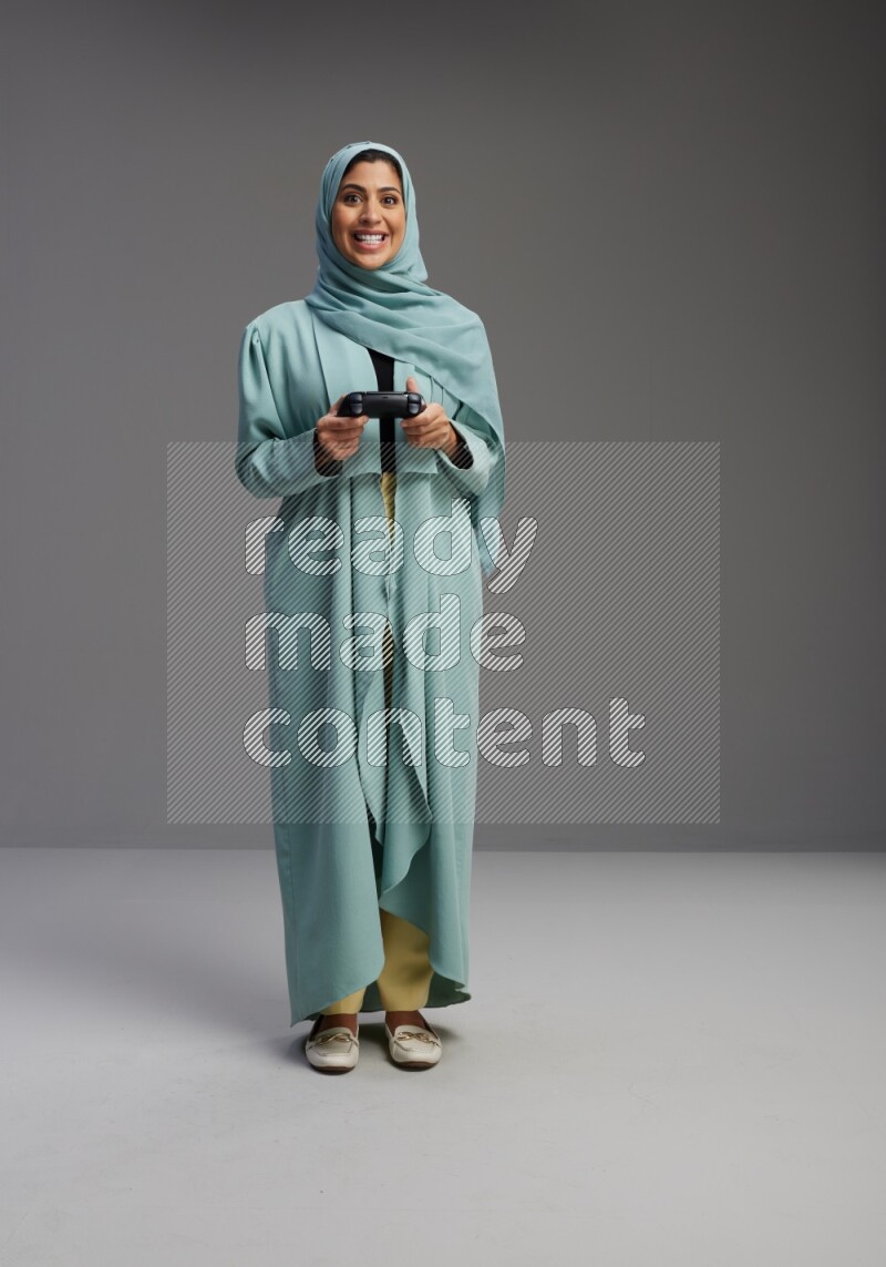 Saudi Woman wearing Abaya standing Playing Games on Gray background