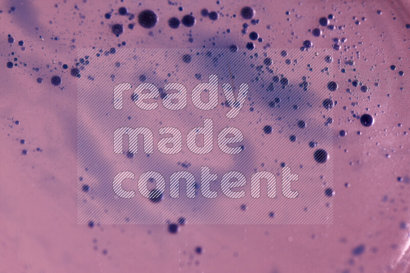 Close-ups of abstract blue watercolor drops on oil Surface on pink background