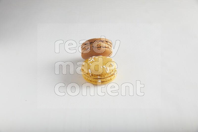 45º Shot of of two assorted Brown Irish Cream, and Yellow Piña Colada macarons on white background