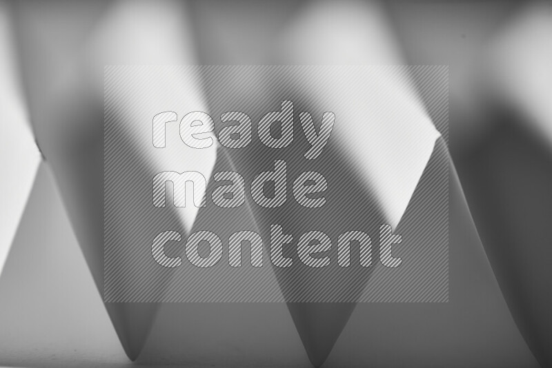 A close-up abstract image showing sharp geometric paper folds in grey gradients