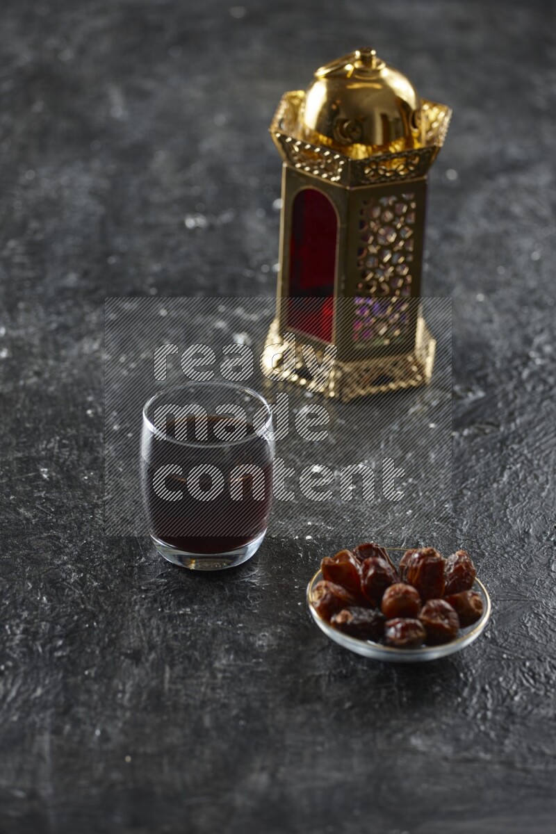 A golden lantern with different drinks, dates, nuts, prayer beads and quran on textured black background