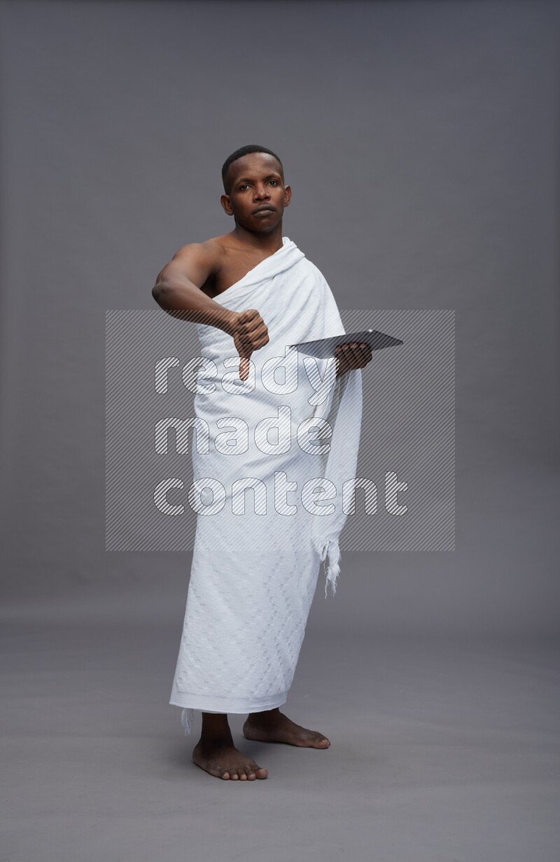 A man wearing Ehram Standing working on tablet on gray background