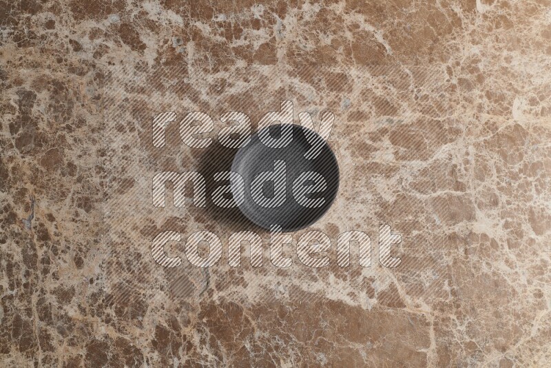 A black pottery bowl on beige marble background