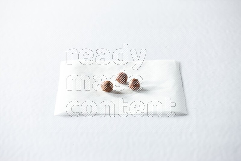 3 peeled hazelnuts on a piece of paper on a white background in different angles