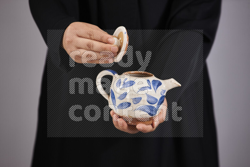 A woman in black abaya holding different pottery essentials in different positions