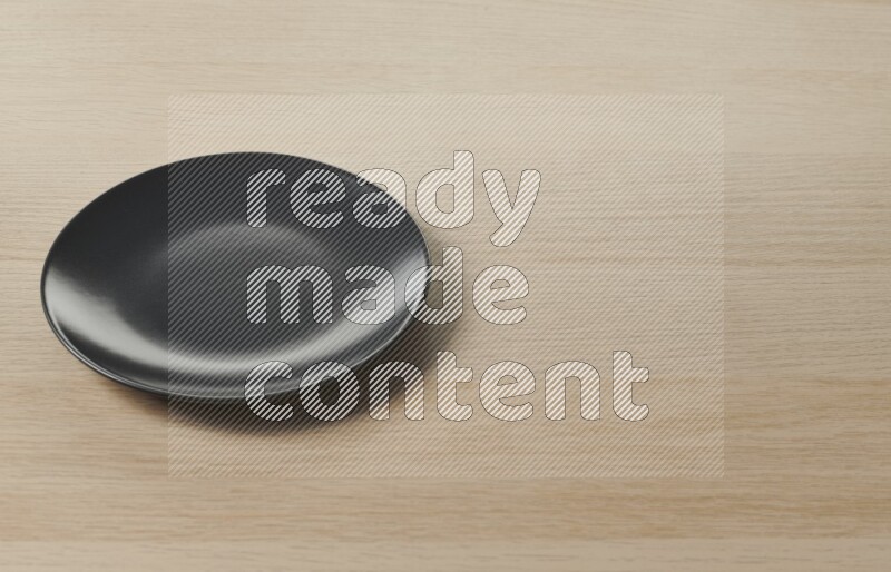 طبق دائري من السيراميك باللون الأسود على خلفية خشبية فاتحة