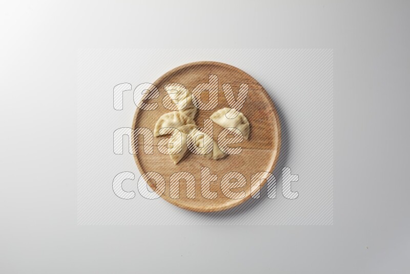 Five Sambosas on a wooden round plate on a white background