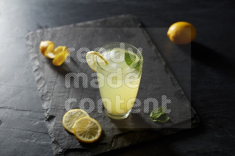 A glass of lemon juice with a lemon slice on black background