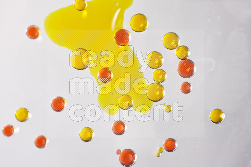 Close-ups of abstract yellow and red watercolor drops on oil Surface on white background