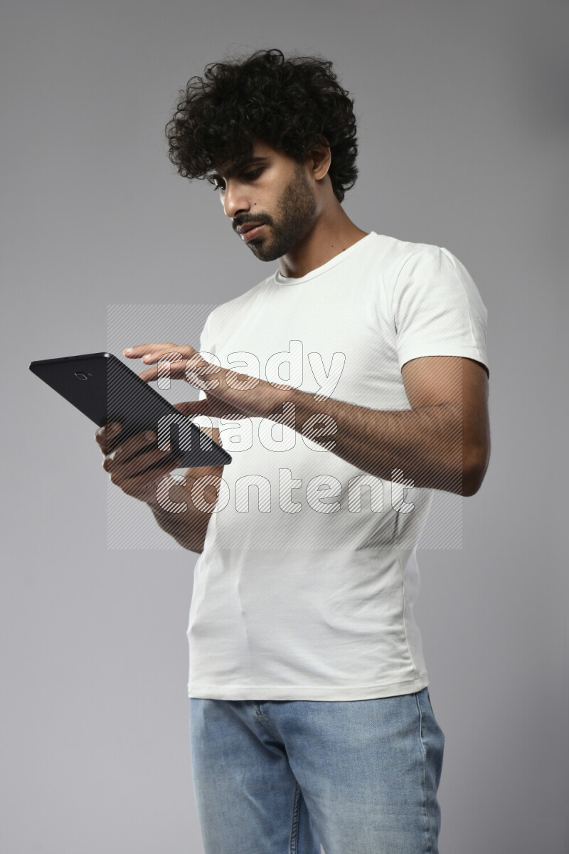 A man wearing casual standing and browsing on a tablet on white background