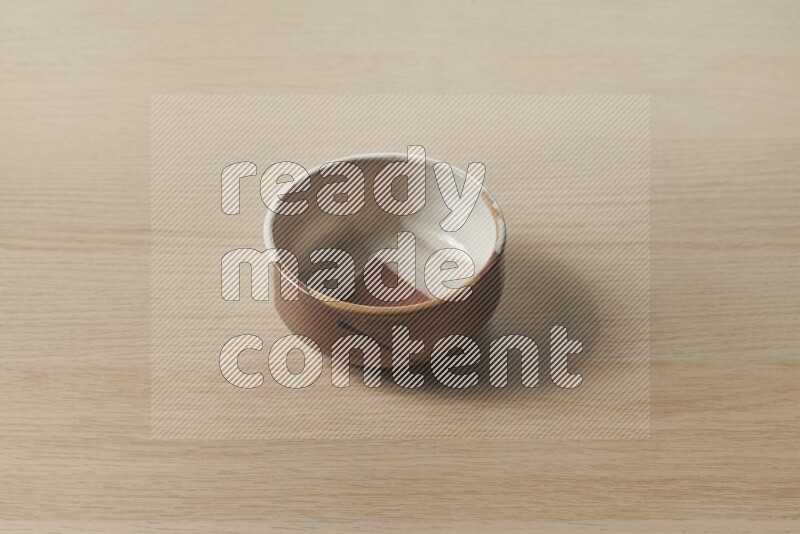 A multicolored pottery bowl on light wooden background
