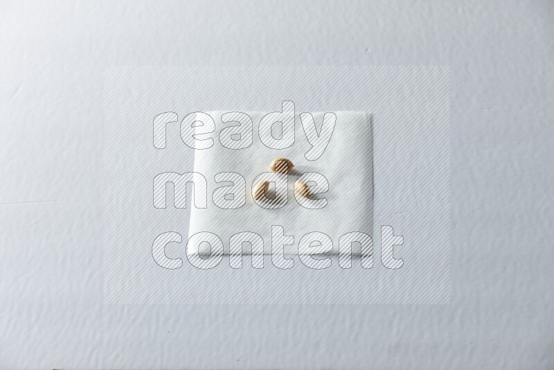 3 peeled peanuts on a piece of paper on a white background in different angles