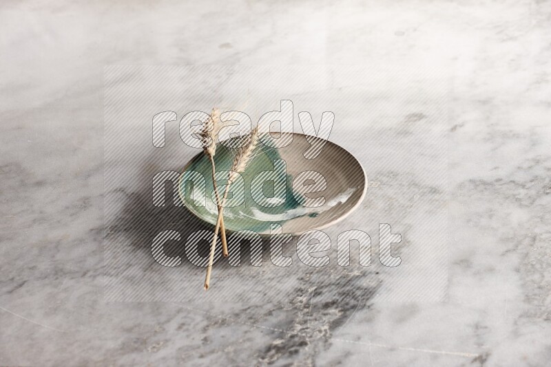 Wheat stalks on multicolored pottery plate on grey marble background
