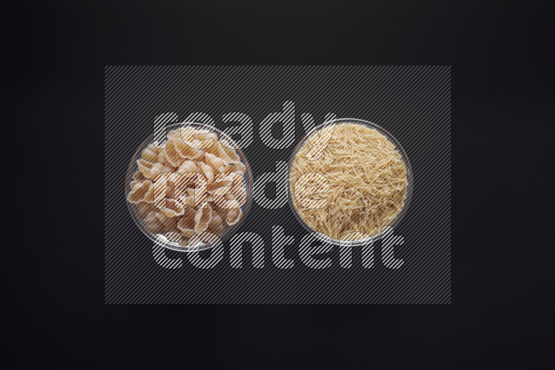 Different pasta types in glass bowls on black background