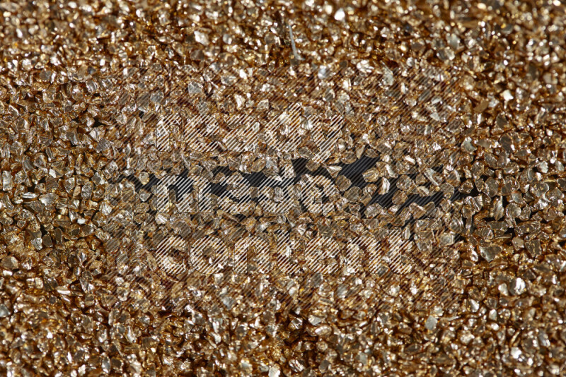 Gold shimmering fragments of glass scattered on a black background