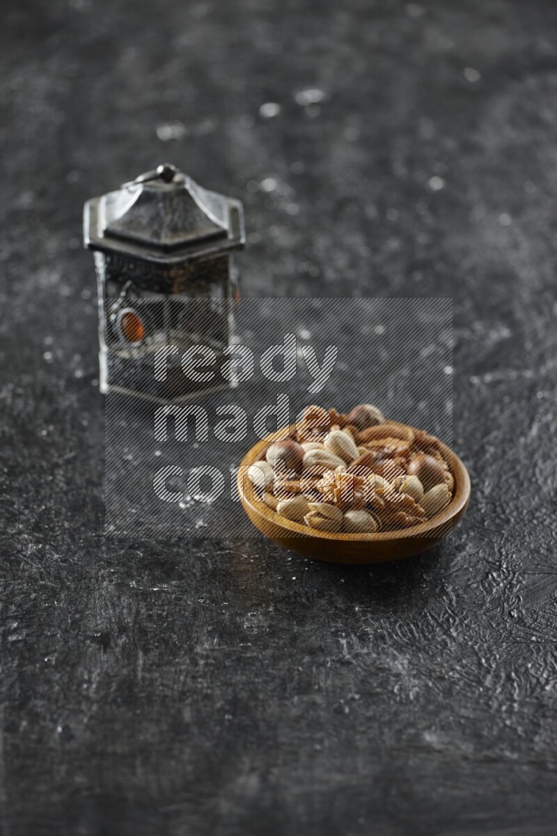 A silver lantern with different drinks, dates, nuts, prayer beads and quran on textured black background