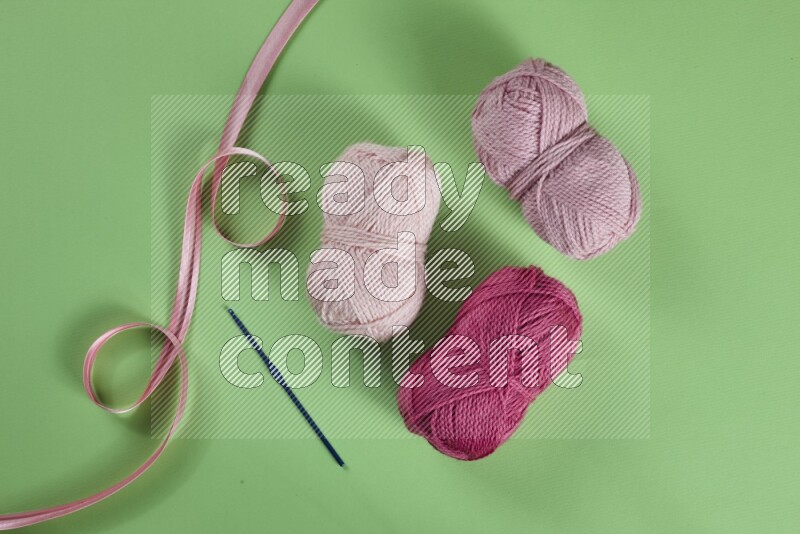 A pink collection of sewing and tailoring tools arranged on a green background
