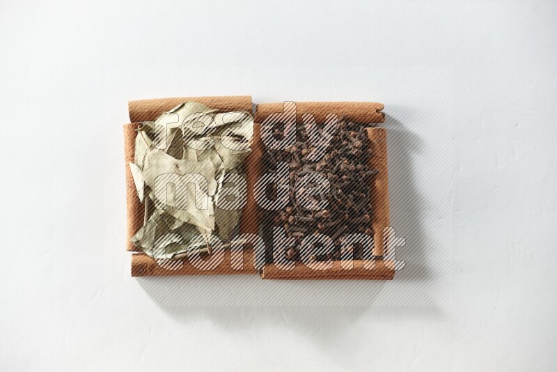 2 squares of cinnamon sticks full of cloves and bay laurel leaves on white flooring