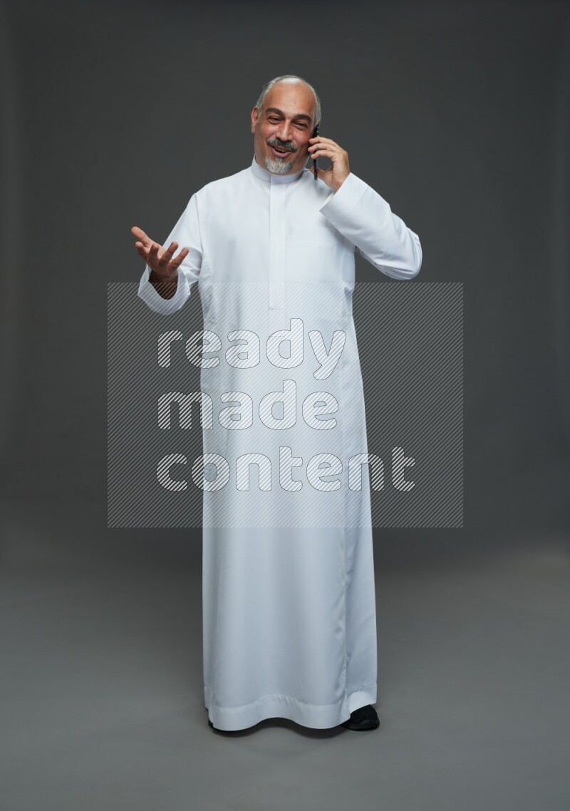 Saudi man without shomag Standing talking on phone on gray background
