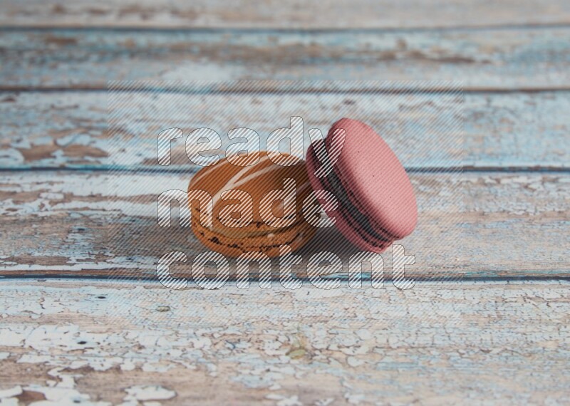 45º Shot of of two assorted Brown Irish Cream, and Red Cherry macarons  on light blue background